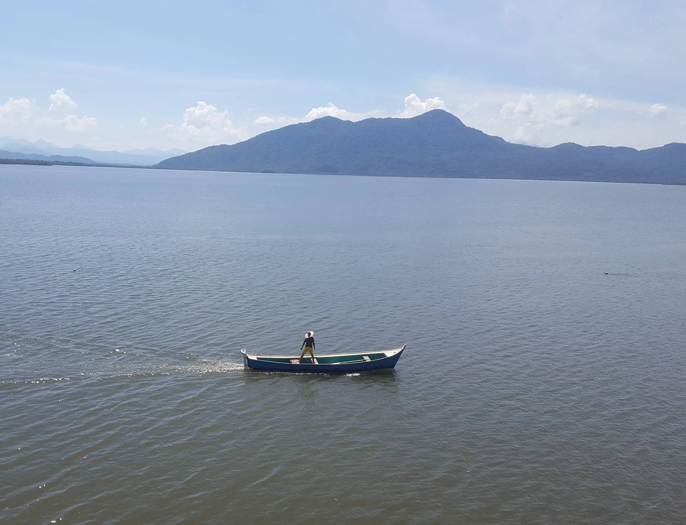 Barco de pesca na baía com montanhas ao fundo