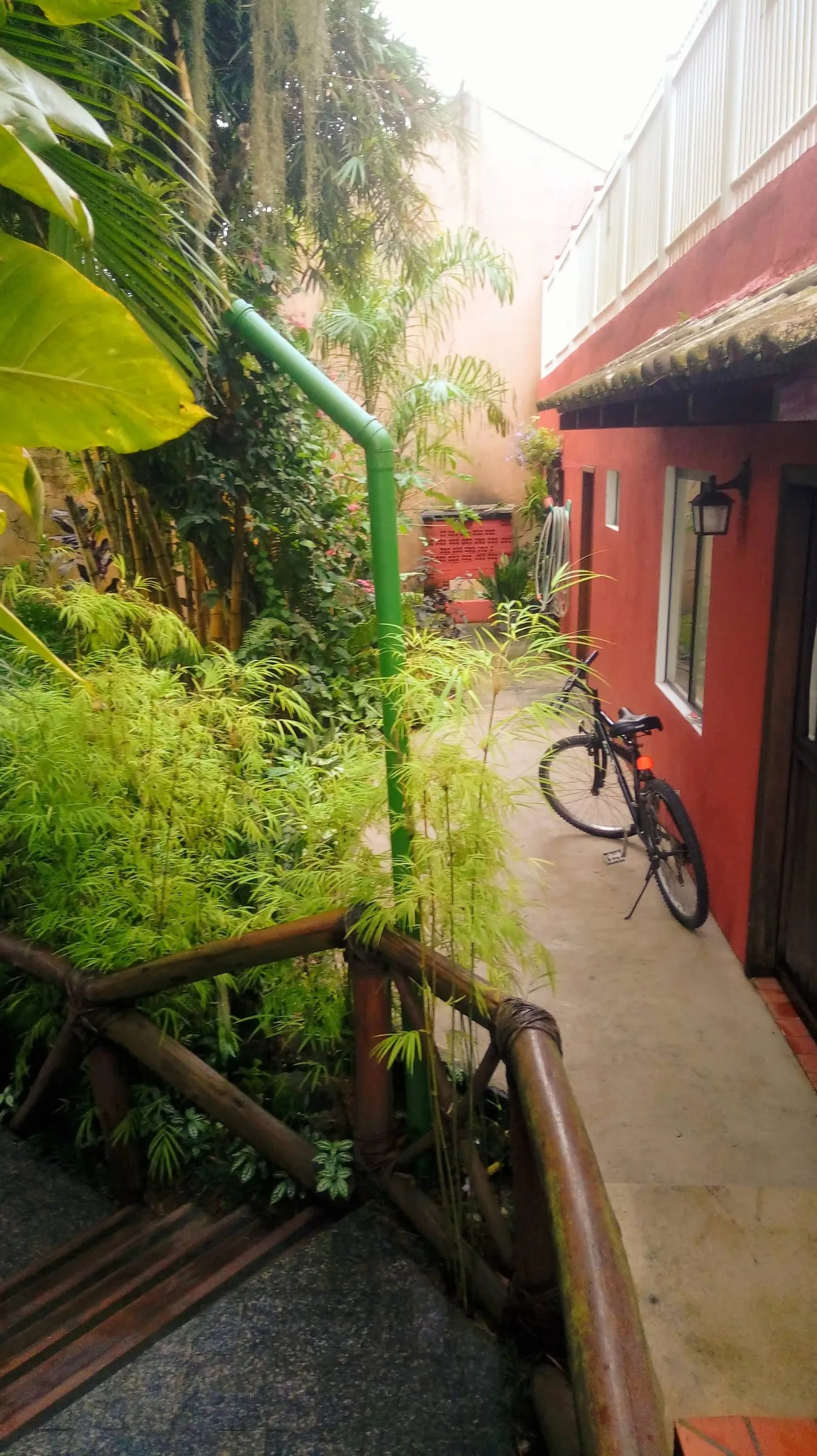 Caminho no jardim com bicicleta encostada na parede vermelha