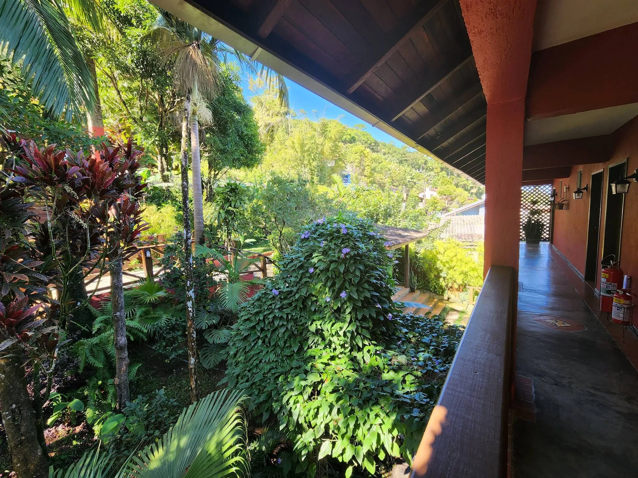 Corredor da varanda com vista para o jardim e palmeiras