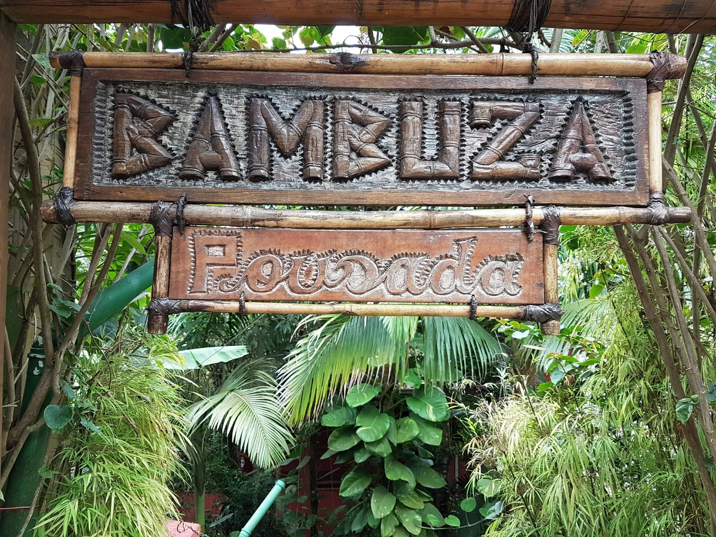 Placa de madeira entalhada com o nome Pousada Bambuza na entrada