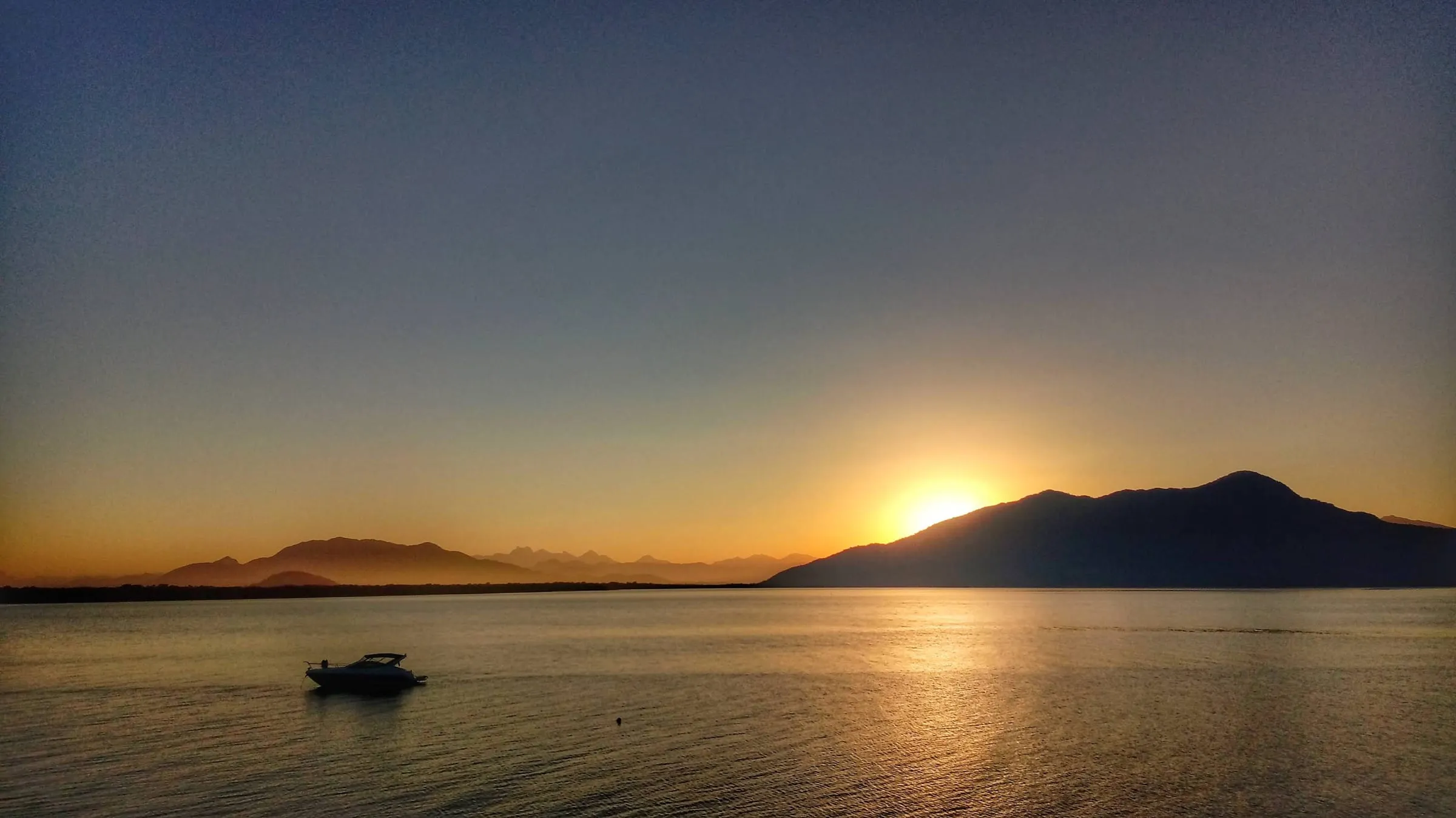 Pôr do sol na baía com um barco ao longe