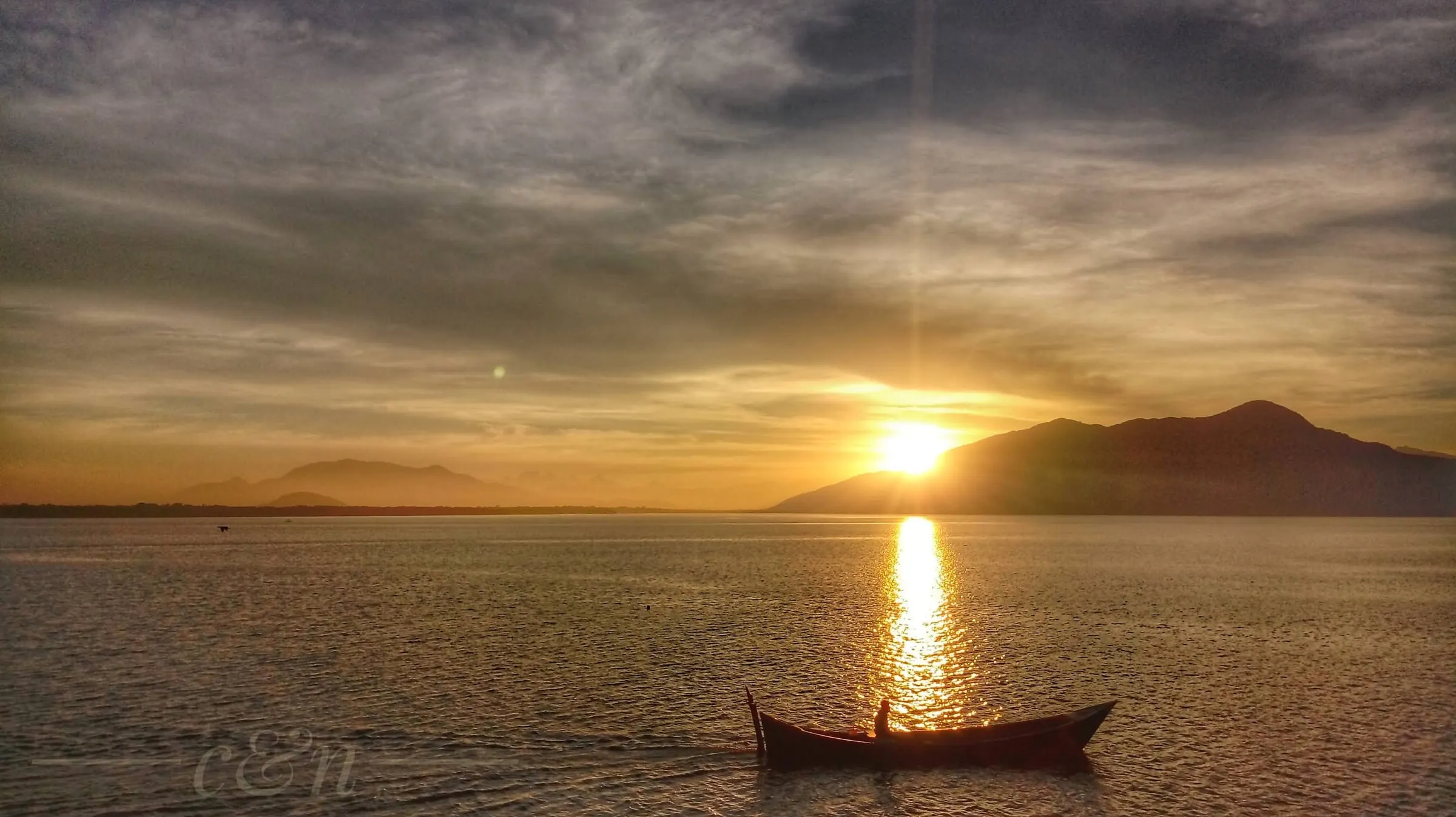 Pôr do sol na baía com um barco solitário