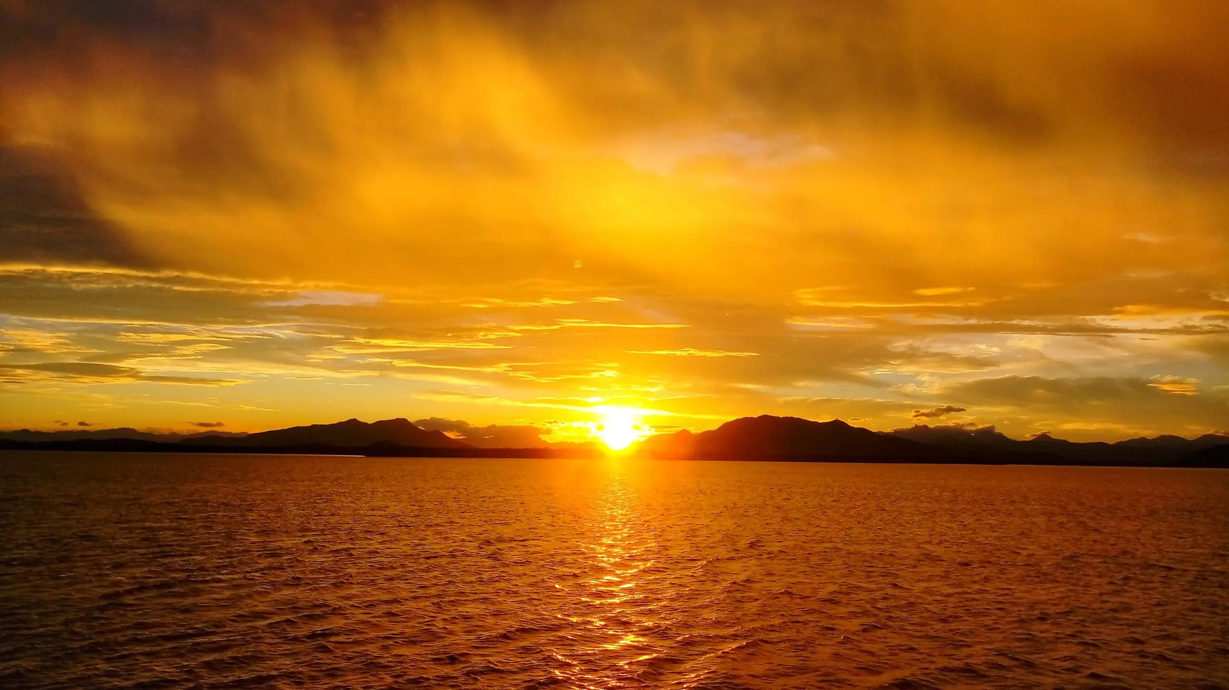 Pôr do sol com céu laranja sobre a Baía de Guaraqueçaba