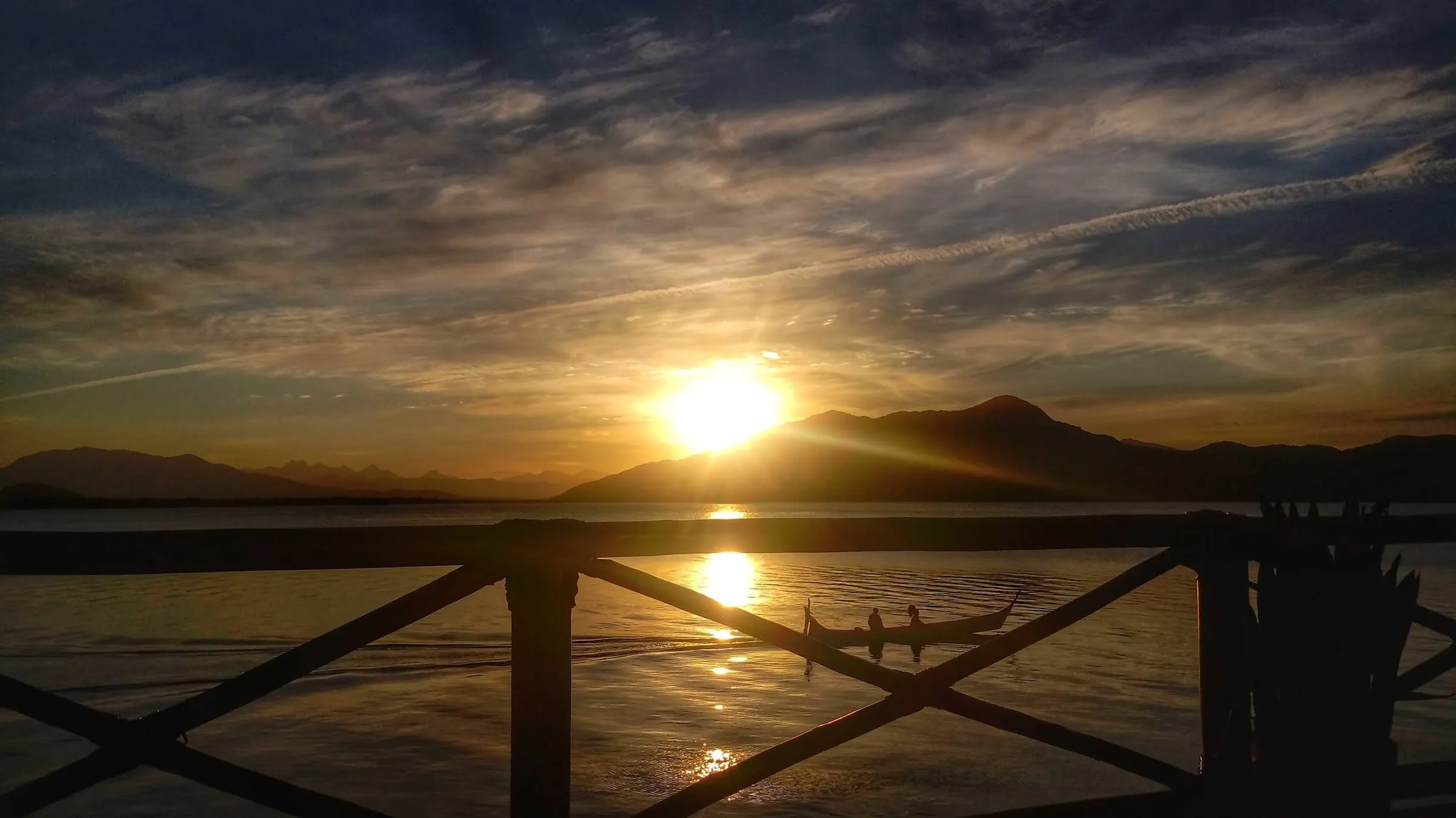 Pôr do sol visto do deck, com barco na baía