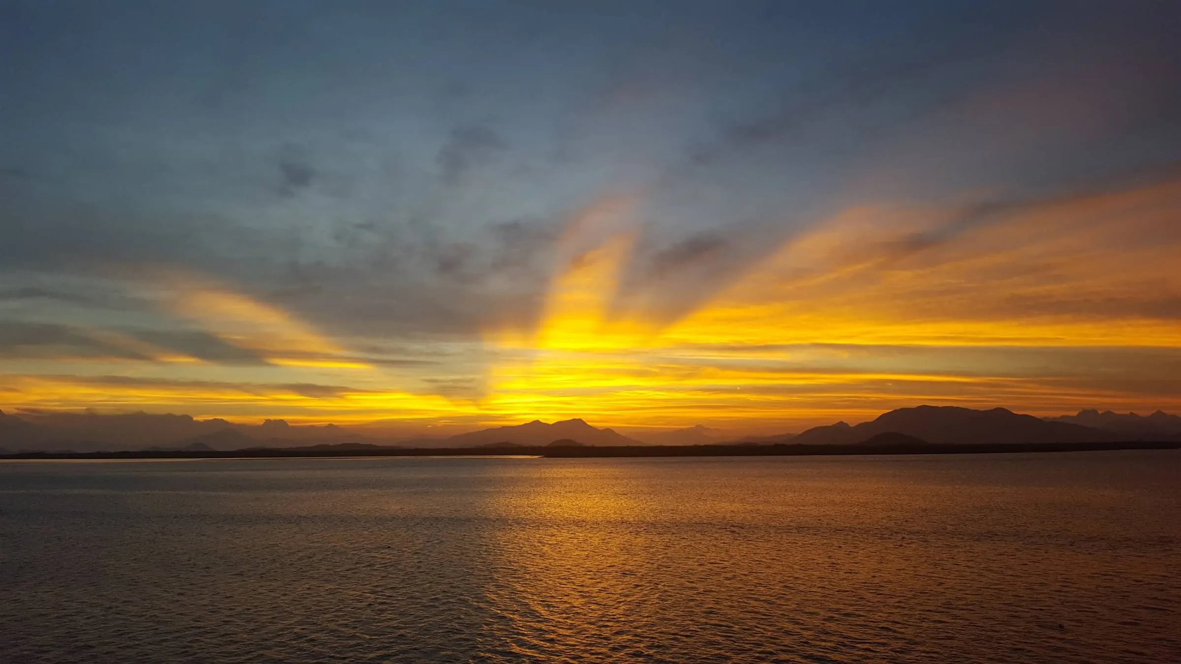 Raios de luz do pôr do sol refletidos na baía