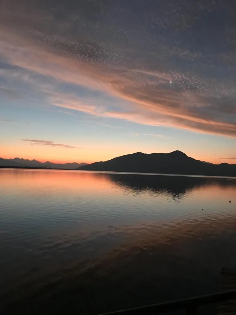 Pôr do sol sobre a baía com silhueta de montanhas