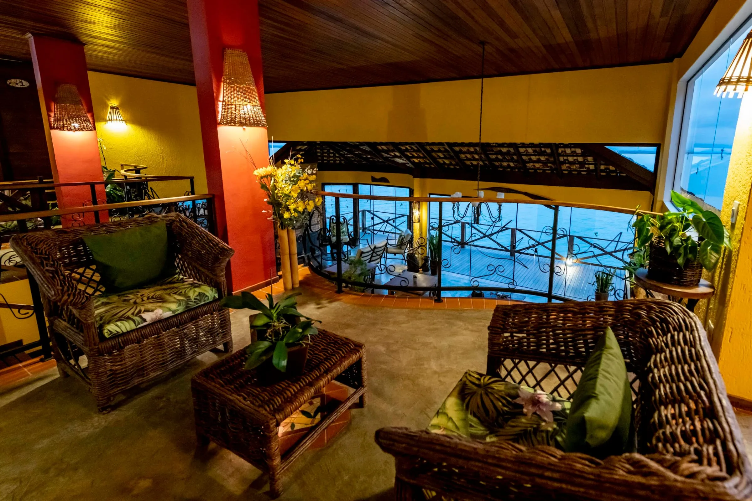 Sala de estar à noite com sofás de vime e vista para a baía iluminada